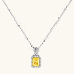 Yellow moissanite jewelry set with emerald-cut stones in sterling silver halo settings on white background.