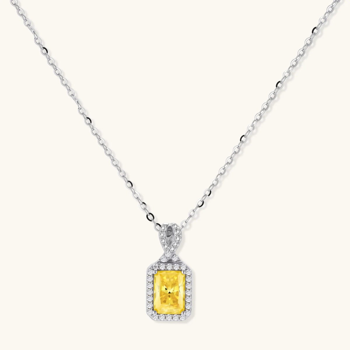 Yellow moissanite jewelry set with emerald-cut stones in sterling silver halo settings on white background.