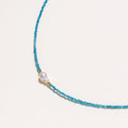 Dainty teal apatite beaded necklace with a single freshwater pearl centerpiece flanked by two small gold beads, adjustable gold clasp.