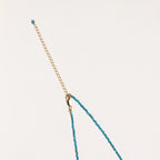 Dainty teal apatite beaded necklace with a single freshwater pearl centerpiece flanked by two small gold beads, adjustable gold clasp.