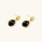 Gold-plated rippled stud earrings with black agate stone drops on white background
