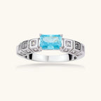 Geometric silver-plated ring with rectangular aqua cubic zirconia center and square crystal details on adjustable band.