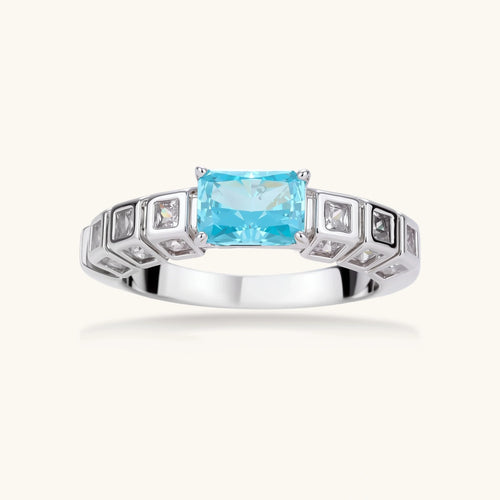 Geometric silver-plated ring with rectangular aqua cubic zirconia center and square crystal details on adjustable band.